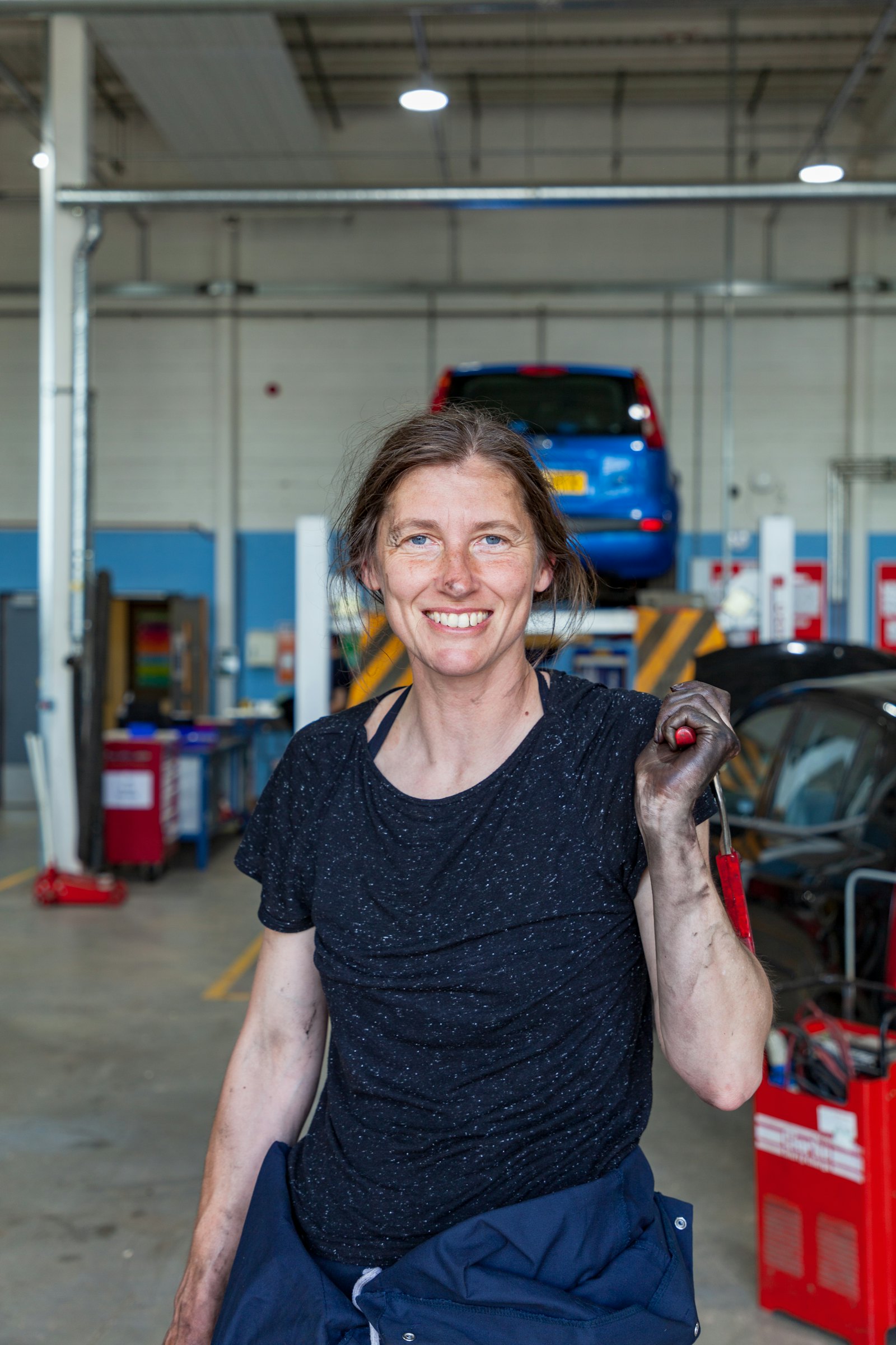 A mechanic holding a wrench in her garage